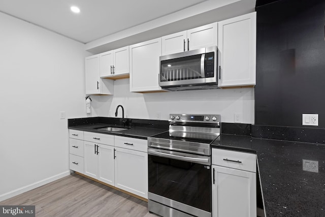 2118 Wilkens Ave, Baltimore, MD 21223 - kitchen with stainless steel appliances, a sink, light wood-type flooring, white cabinets, and baseboards