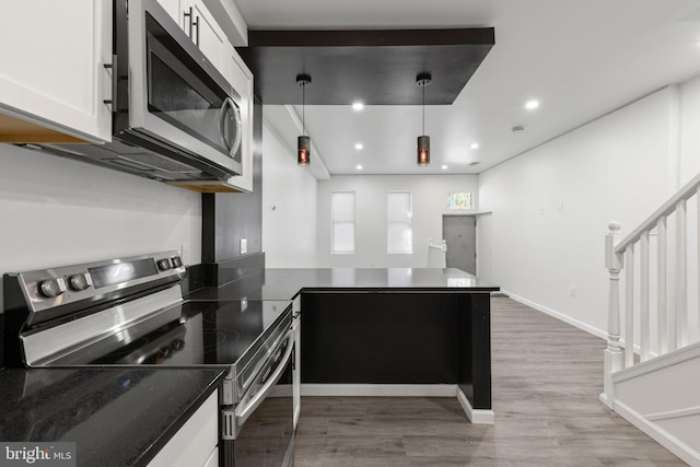 2118 Wilkens Ave, Baltimore, MD 21223 - kitchen with appliances with stainless steel finishes, white cabinets, light wood finished floors, a peninsula, and dark stone countertops