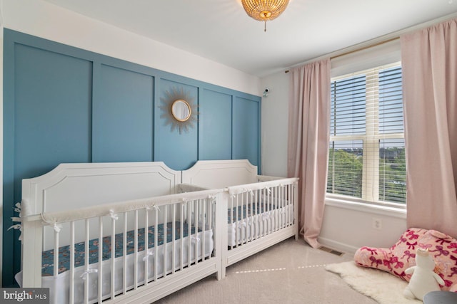 bedroom featuring baseboards, carpet, and a crib