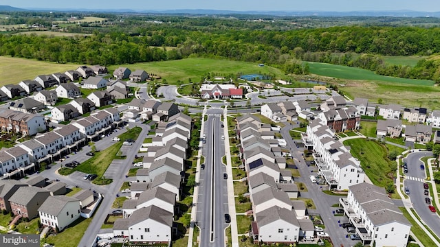 view of property location with nearby suburban area, a golf club, and a forest