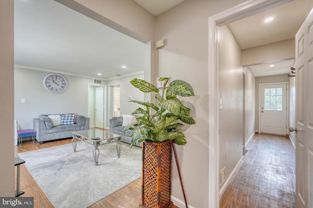 corridor featuring wood finished floors, baseboards, recessed lighting, and crown molding