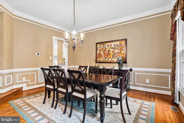 3747 Spicebush Dr, Frederick, MD 21704 - dining room with a chandelier, ornamental molding, wood finished floors, and a wainscoted wall