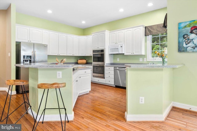 3747 Spicebush Dr, Frederick, MD 21704 - kitchen featuring stainless steel appliances, a kitchen breakfast bar, white cabinets, light wood finished floors, and recessed lighting