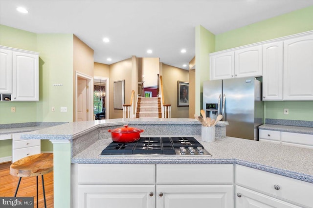 3747 Spicebush Dr, Frederick, MD 21704 - kitchen with stainless steel appliances, white cabinets, light countertops, a kitchen breakfast bar, and wood finished floors