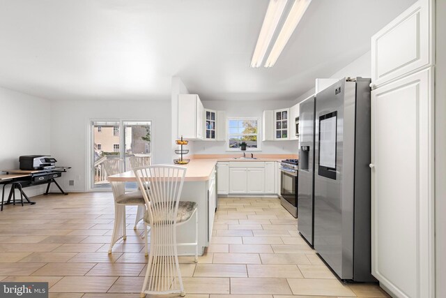 316 Nautilus Dr, Manahawkin, NJ 08050 - kitchen featuring stainless steel appliances, a peninsula, glass insert cabinets, a breakfast bar, and white cabinetry