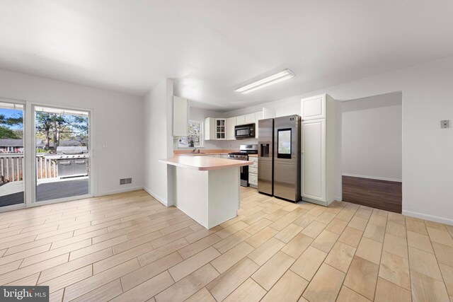 316 Nautilus Dr, Manahawkin, NJ 08050 - kitchen featuring stainless steel appliances, a peninsula, glass insert cabinets, and white cabinets