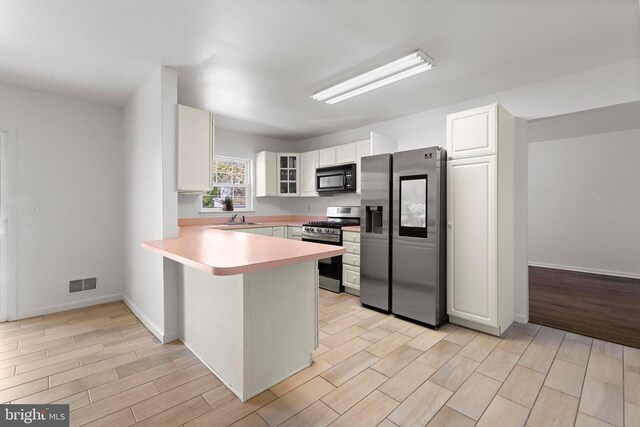 316 Nautilus Dr, Manahawkin, NJ 08050 - kitchen featuring stainless steel appliances, a peninsula, light countertops, white cabinets, and light wood-type flooring