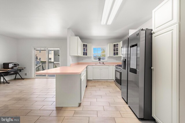 316 Nautilus Dr, Manahawkin, NJ 08050 - kitchen featuring stainless steel appliances, a peninsula, a sink, glass insert cabinets, and light countertops
