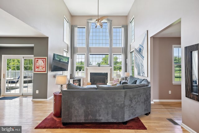 22 Sawgrass Dr, Mount Holly, NJ 08060 - living area featuring a ceiling fan, light wood-style flooring, a glass covered fireplace, baseboards, and a towering ceiling