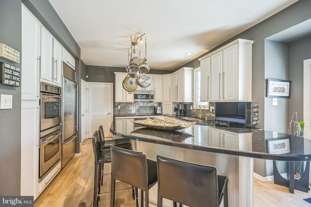 22 Sawgrass Dr, Mount Holly, NJ 08060 - kitchen with appliances with stainless steel finishes, a sink, tasteful backsplash, light wood-style floors, and dark stone countertops
