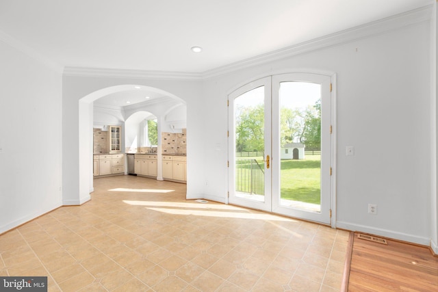 entryway featuring crown molding, baseboards, arched walkways, and recessed lighting