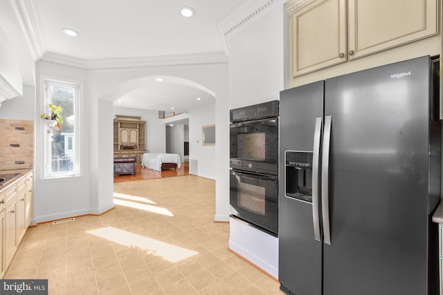 kitchen with stainless steel refrigerator with ice dispenser, cream cabinets, crown molding, arched walkways, and backsplash