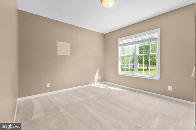 spare room featuring baseboards and light carpet