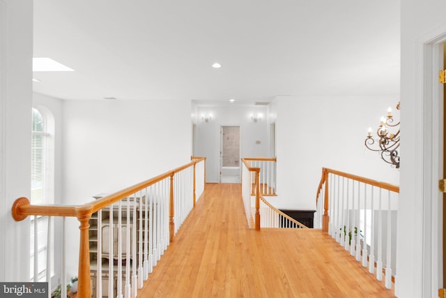 hallway featuring an upstairs landing, wood finished floors, a skylight, and recessed lighting