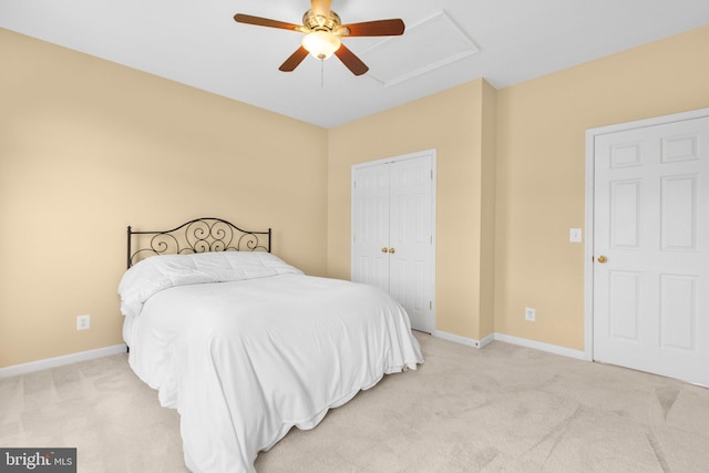 bedroom featuring light colored carpet, baseboards, attic access, a closet, and a ceiling fan