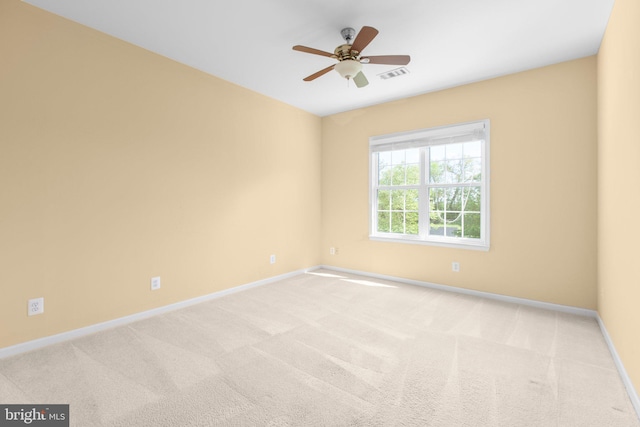 carpeted spare room featuring baseboards and a ceiling fan