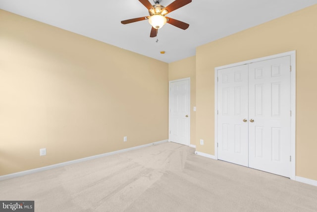 unfurnished bedroom featuring light carpet, baseboards, a closet, and a ceiling fan