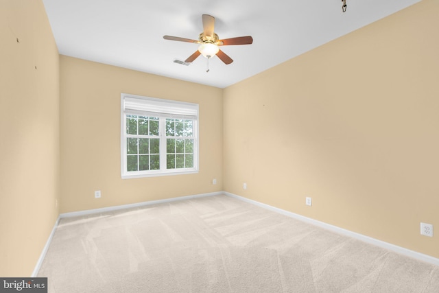 empty room featuring light colored carpet, baseboards, and a ceiling fan