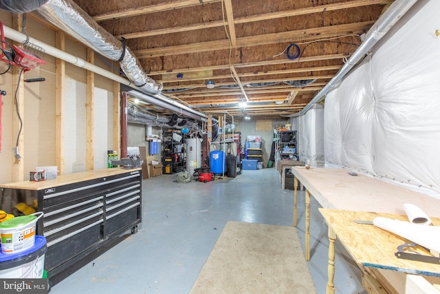 unfinished below grade area featuring water heater and a water pressure tank