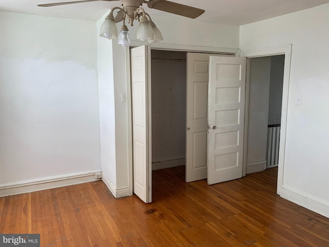 unfurnished bedroom featuring wood-type flooring, a closet, baseboards, and ceiling fan