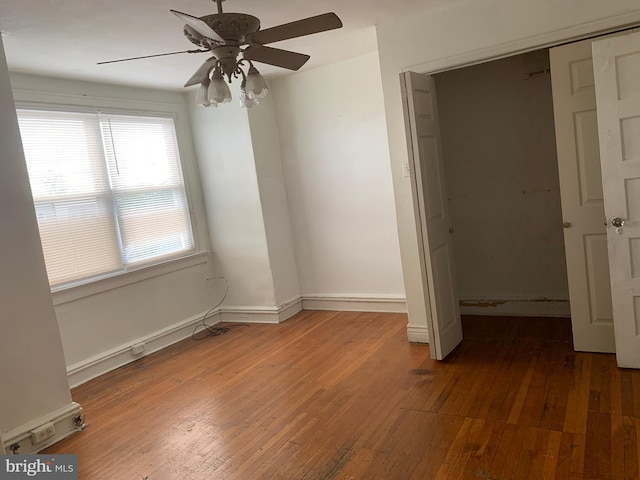 unfurnished bedroom with hardwood / wood-style floors, a closet, baseboards, and a ceiling fan