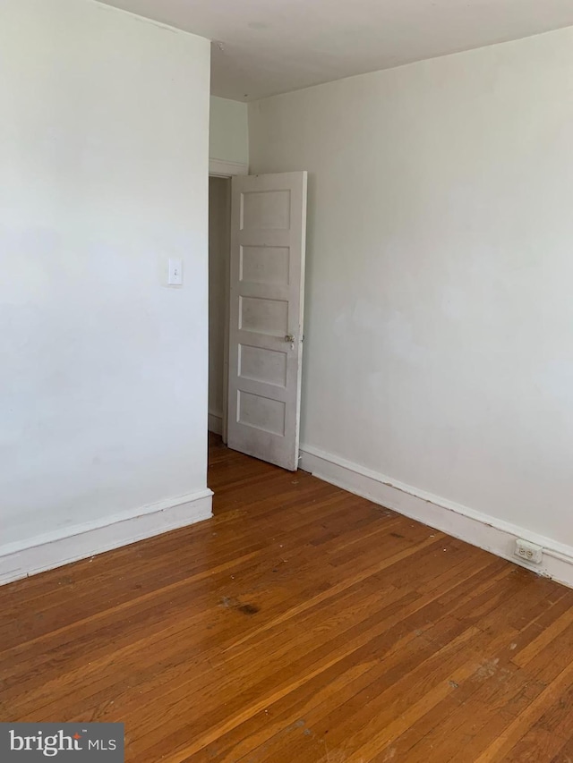 spare room featuring baseboards and hardwood / wood-style flooring