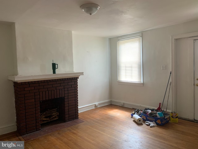 unfurnished living room with wood finished floors and a brick fireplace