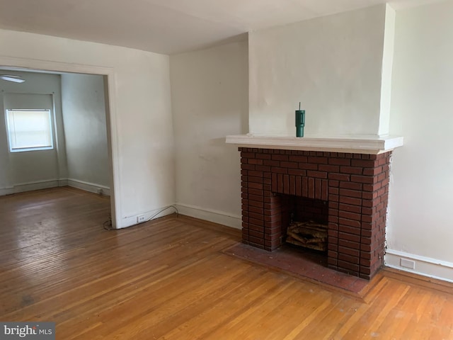 unfurnished living room featuring wood finished floors, a fireplace, and baseboards