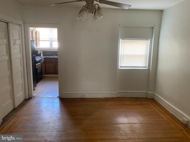unfurnished dining area featuring light wood finished floors, ceiling fan, and baseboards