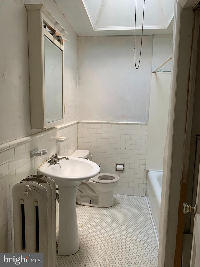 full bath featuring tile walls, toilet, a wainscoted wall, and tile patterned floors