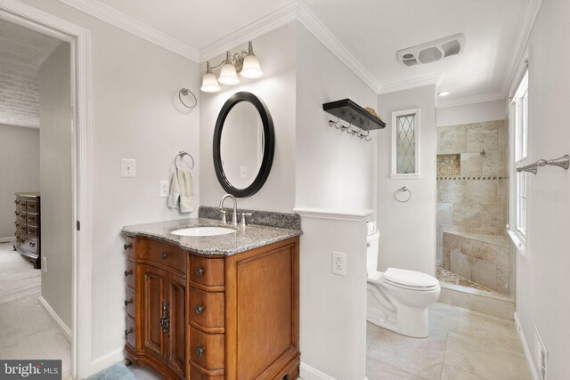 bathroom with tiled shower, toilet, vanity, baseboards, and crown molding