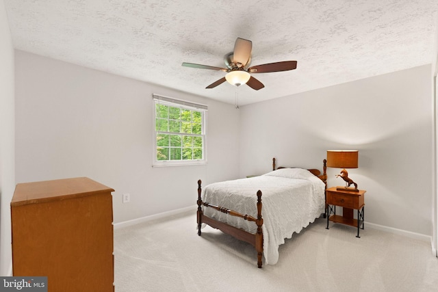 bedroom featuring baseboards, light carpet, a textured ceiling, and a ceiling fan