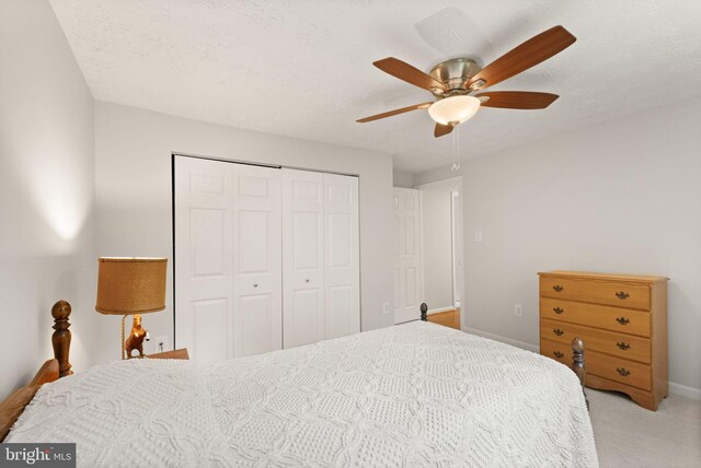 bedroom with a closet, light carpet, baseboards, and a ceiling fan