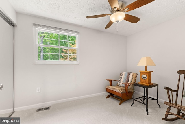living area with carpet, baseboards, ceiling fan, and a textured ceiling
