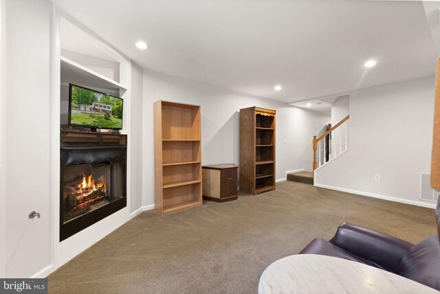 carpeted living area featuring stairway, a lit fireplace, recessed lighting, and baseboards