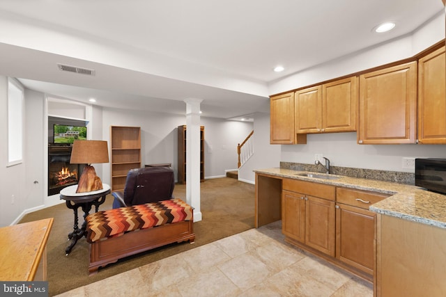 kitchen featuring a sink, a glass covered fireplace, light colored carpet, baseboards, and recessed lighting