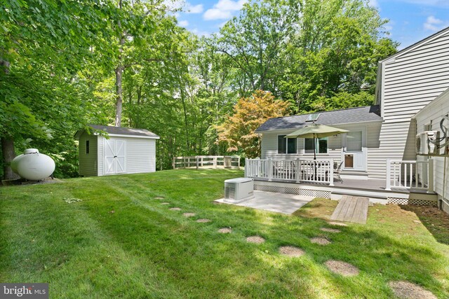 view of yard featuring a deck, a storage shed, and an outbuilding