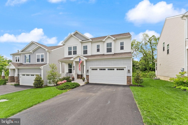 view of front of house featuring an attached garage, driveway, stone siding, and a front lawn