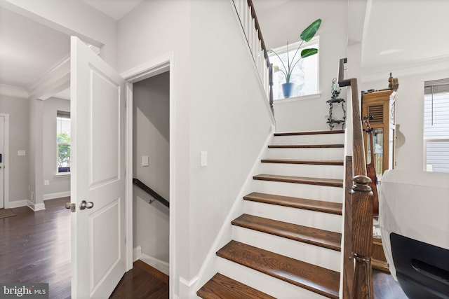 staircase featuring baseboards, wood finished floors, and ornamental molding