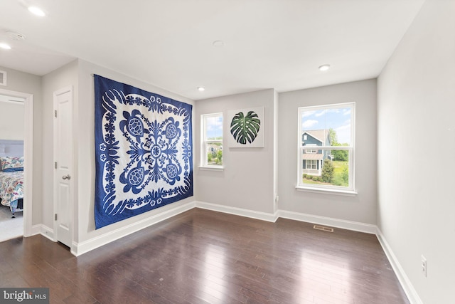 empty room featuring healthy amount of natural light, wood finished floors, baseboards, and recessed lighting