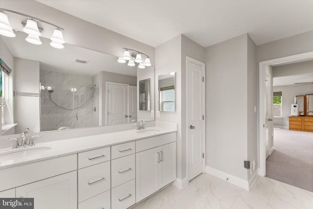 bathroom with a marble finish shower, marble look tile flooring, double vanity, and baseboards
