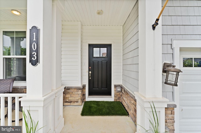 view of exterior entry featuring covered porch and stone siding