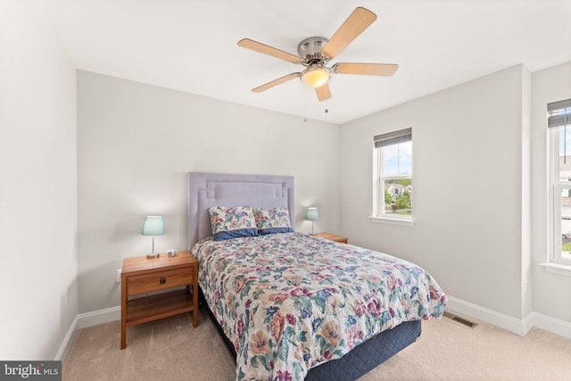 carpeted bedroom featuring multiple windows, baseboards, and ceiling fan