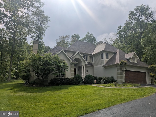 view of front of home featuring a front yard, a garage, roof with shingles, stucco siding, and asphalt driveway
