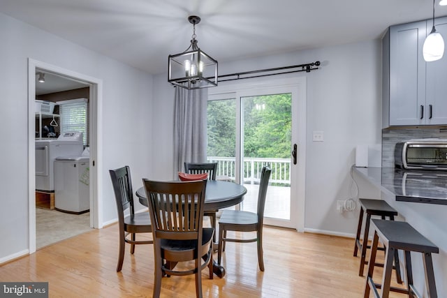 dining room featuring washer and clothes dryer, a chandelier, light wood-style flooring, and baseboards