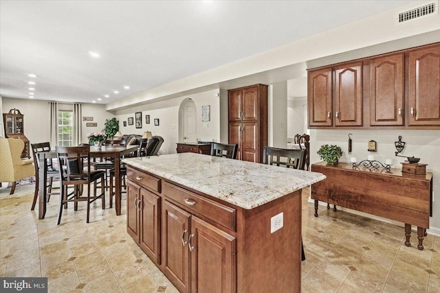 2218 W Greenleaf Dr W, Frederick, MD 21702 - kitchen featuring a kitchen island, arched walkways, recessed lighting, light stone counters, and brown cabinetry