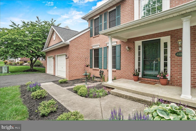 2218 W Greenleaf Dr W, Frederick, MD 21702 - view of exterior entry with a garage, brick siding, driveway, and a porch