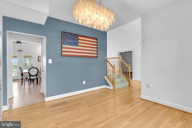 9420 River View Rd, Broomes Island, MD 20615 - spare room with stairway, baseboards, wood finished floors, a ceiling fan, and a chandelier
