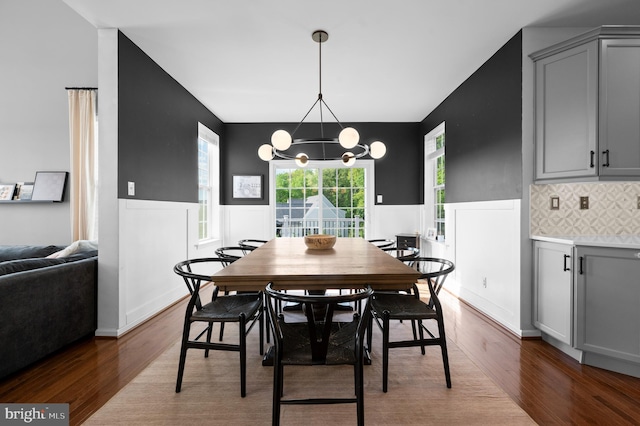 dining space featuring wood finished floors, a wainscoted wall, a chandelier, and plenty of natural light