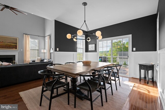 dining area with a chandelier, wainscoting, plenty of natural light, wood finished floors, and a fireplace
